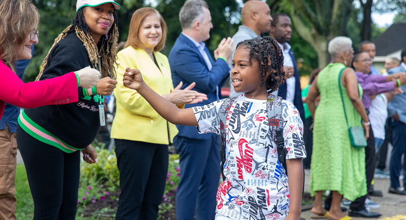 Student fist bumps educators as part of a relationship-building practice at his school