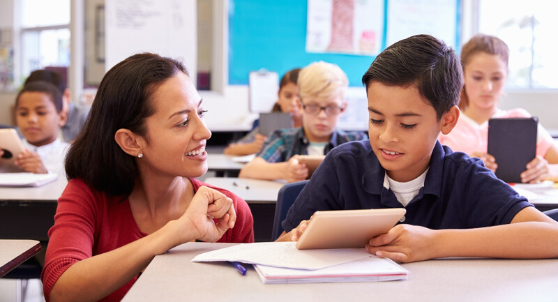 A teacher conferring with an upper elementary school student at their desk during independent work time.