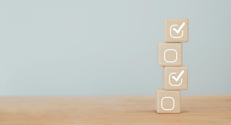 A stack of four wooden blocks, two of which have check marks on them representing student understanding 